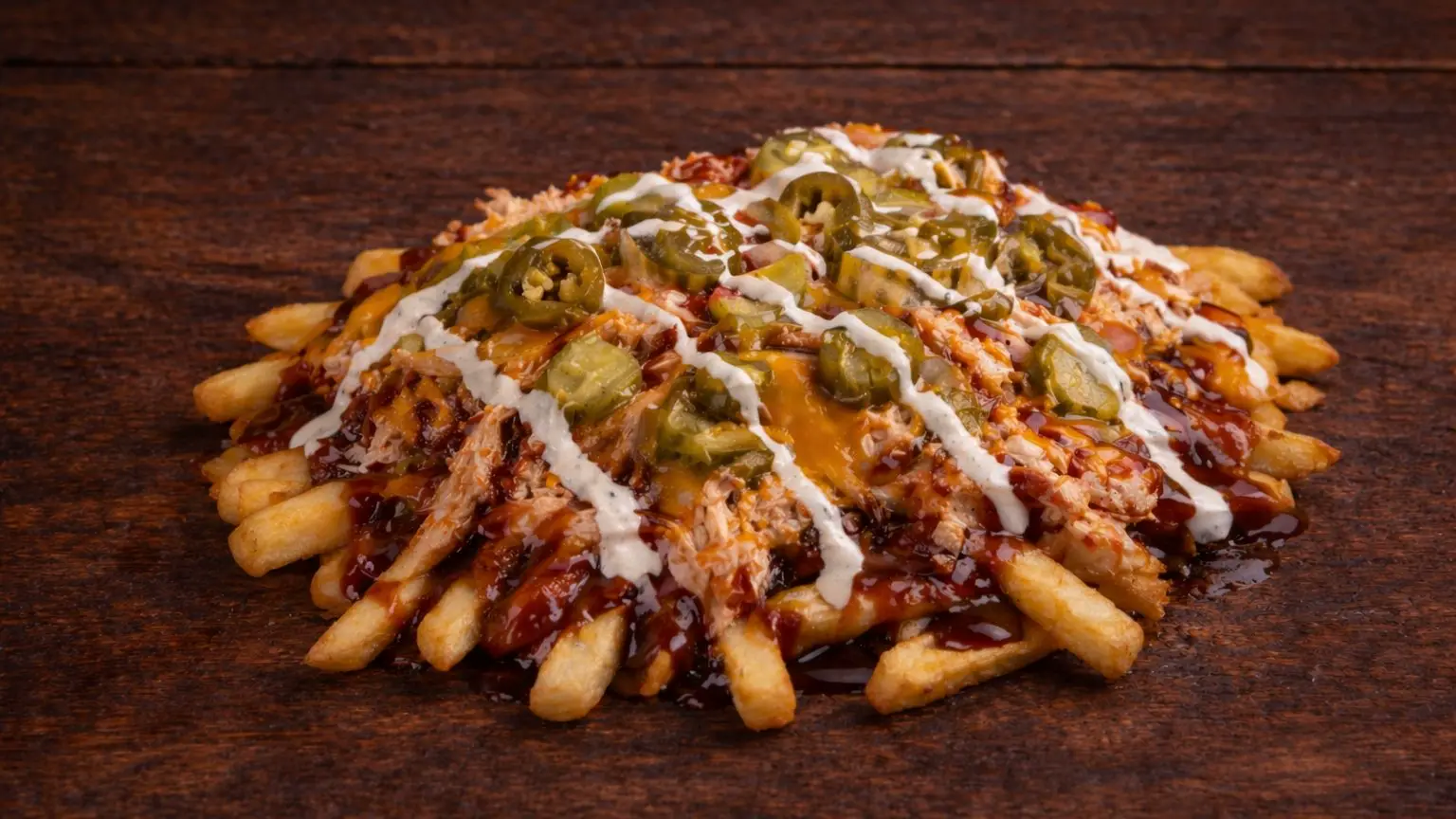 Loaded fries with pulled meat, BBQ sauce, cheese, and jalapeños at Texas Backyard.